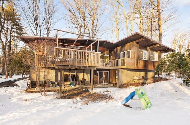 snow covered back of property with a deck