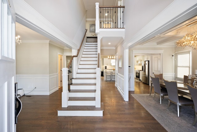 entrance foyer featuring dark hardwood / wood-style flooring, crown molding, and a chandelier