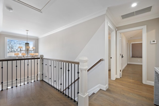 hallway featuring crown molding, wood-type flooring, and a notable chandelier