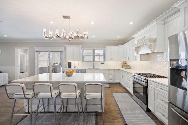 kitchen featuring hanging light fixtures, stainless steel appliances, a center island, and white cabinets