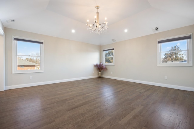 spare room featuring dark wood-type flooring, lofted ceiling, and an inviting chandelier