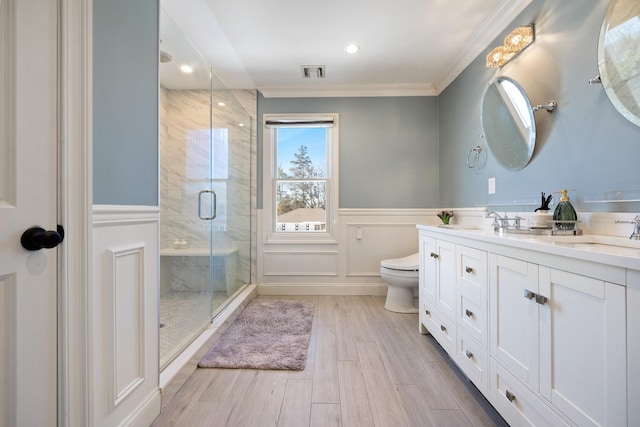 bathroom featuring crown molding, hardwood / wood-style floors, vanity, a shower with shower door, and toilet