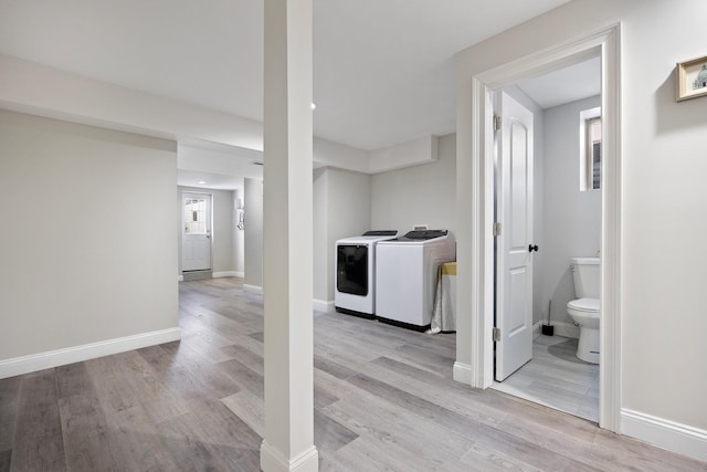 clothes washing area with washer and clothes dryer and light hardwood / wood-style flooring