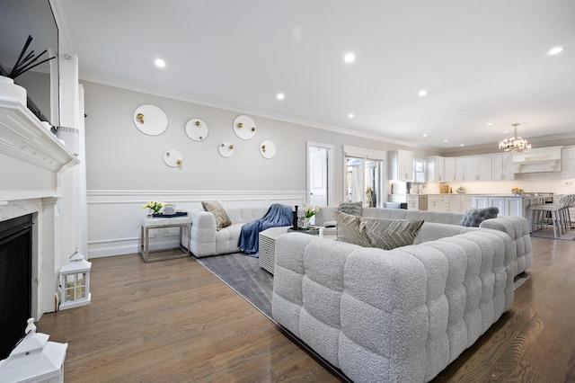 living room with dark hardwood / wood-style flooring, a high end fireplace, ornamental molding, and an inviting chandelier