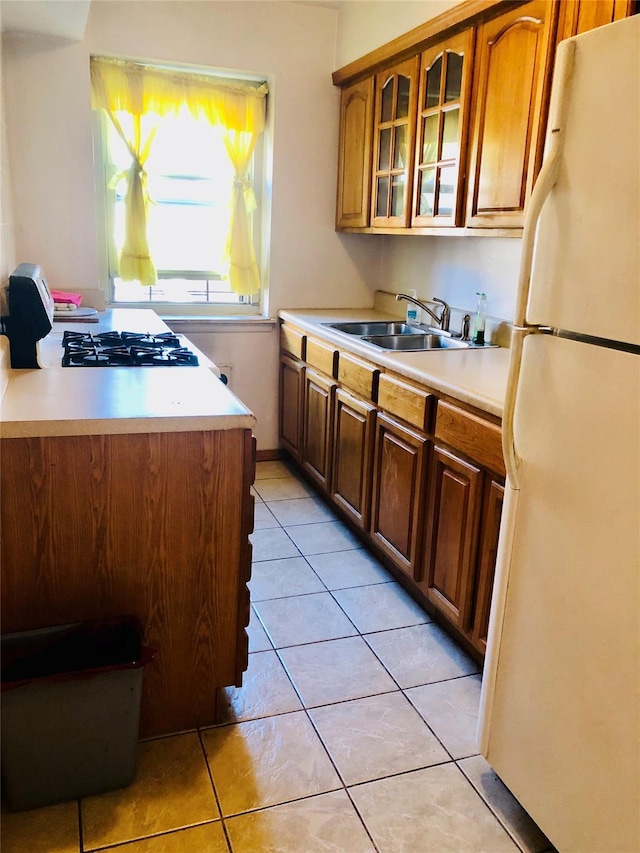 kitchen with light tile patterned flooring, white fridge, sink, and stove