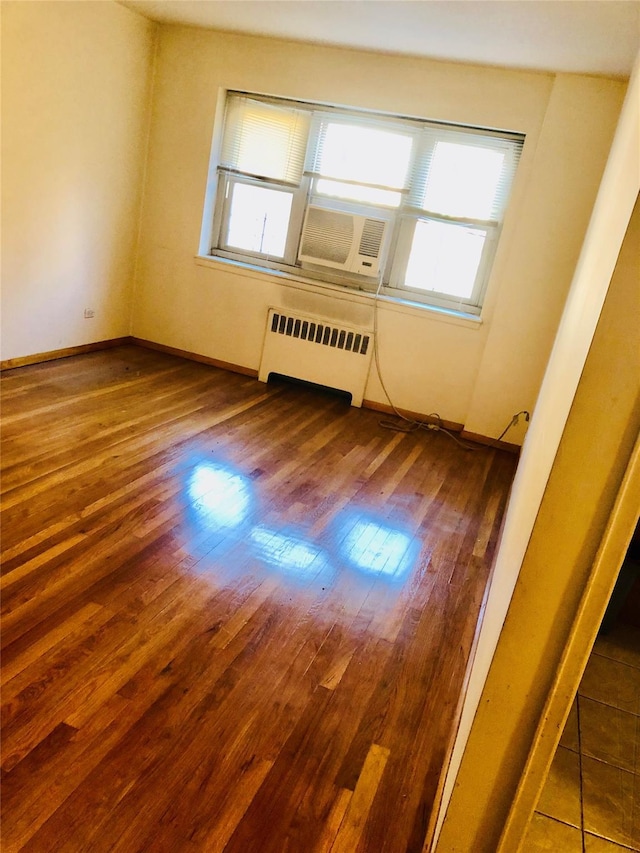 empty room featuring baseboards, dark wood finished floors, and radiator