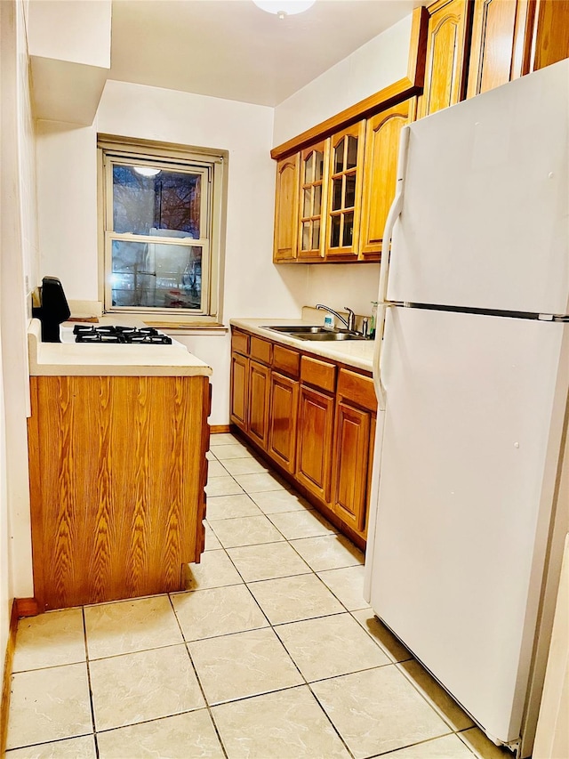 kitchen featuring light countertops, white appliances, glass insert cabinets, and brown cabinets