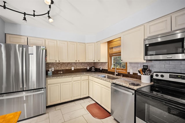 kitchen with appliances with stainless steel finishes, sink, cream cabinets, and backsplash