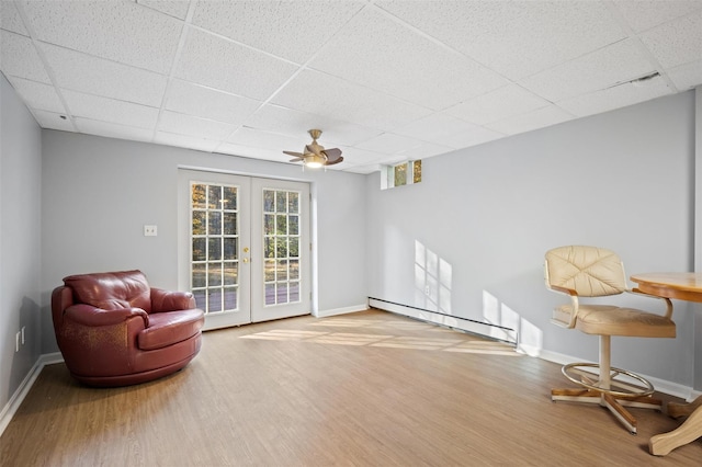 living area with hardwood / wood-style flooring, a baseboard heating unit, a drop ceiling, and french doors