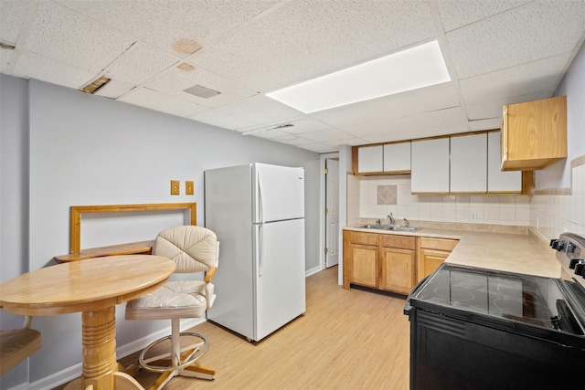 kitchen with electric stove, sink, backsplash, white refrigerator, and light wood-type flooring