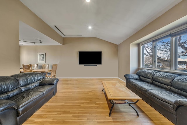 living room featuring lofted ceiling, light hardwood / wood-style flooring, and rail lighting