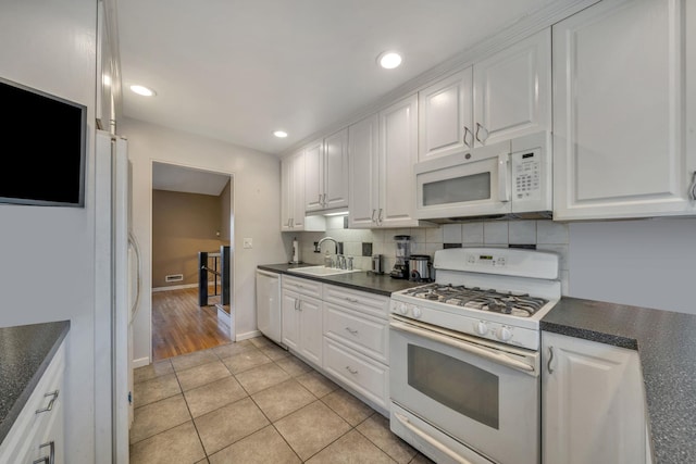 kitchen featuring sink, light tile patterned floors, white appliances, decorative backsplash, and white cabinets