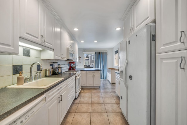 kitchen featuring sink, backsplash, white cabinets, light tile patterned floors, and white appliances