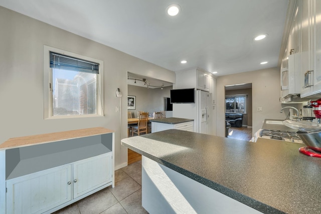 kitchen featuring white cabinetry, kitchen peninsula, sink, and a wealth of natural light