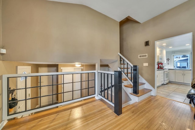 staircase featuring wood-type flooring and vaulted ceiling