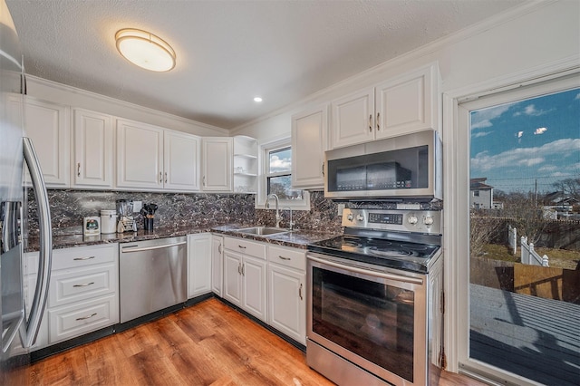 kitchen with white cabinetry, sink, ornamental molding, stainless steel appliances, and light wood-type flooring