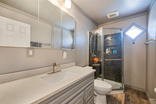 bathroom featuring hardwood / wood-style flooring, ornamental molding, vanity, toilet, and a shower with door