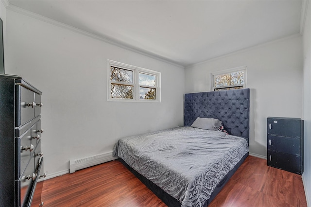 bedroom with crown molding, a baseboard heating unit, and dark wood-type flooring