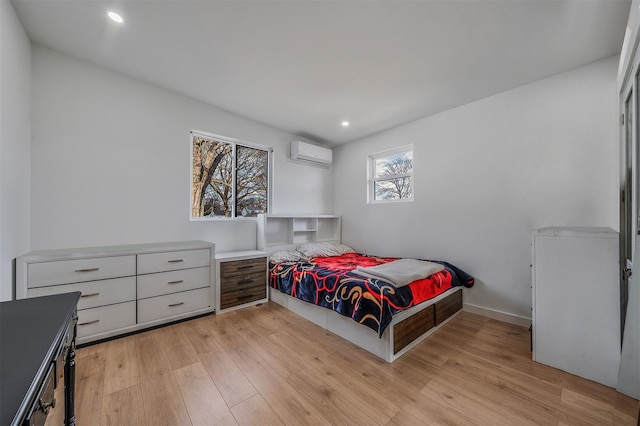 bedroom with a wall unit AC and light wood-type flooring