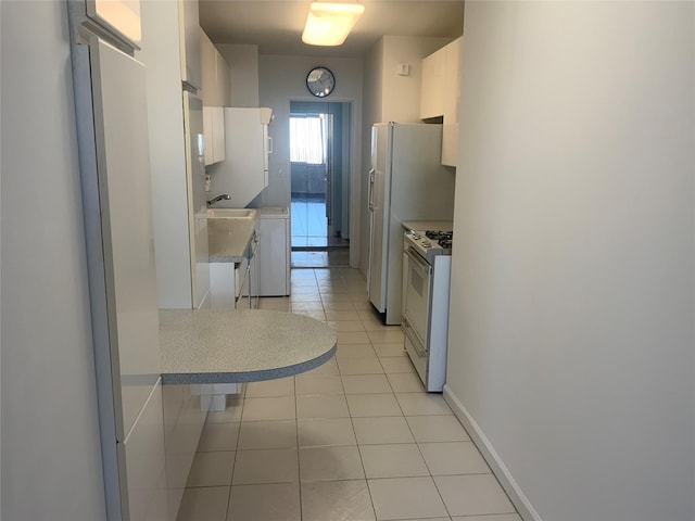 kitchen featuring light tile patterned flooring, white cabinetry, sink, and white gas stove