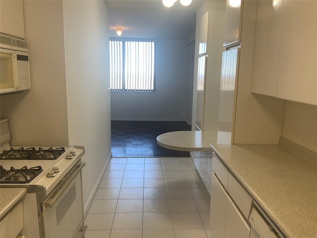 kitchen featuring light tile patterned floors, white appliances, and white cabinets