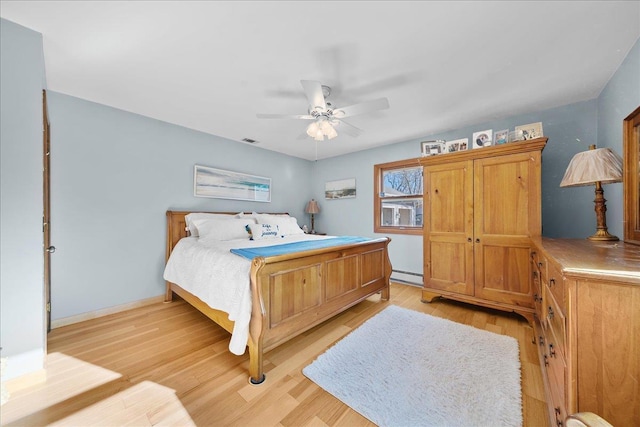 bedroom featuring ceiling fan, light hardwood / wood-style flooring, and a baseboard heating unit