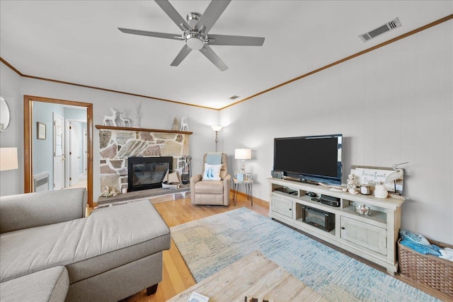 living room featuring a fireplace, wood-type flooring, ornamental molding, and ceiling fan