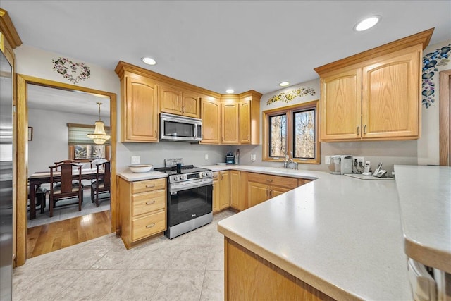 kitchen with appliances with stainless steel finishes, a wealth of natural light, light brown cabinets, and light tile patterned floors