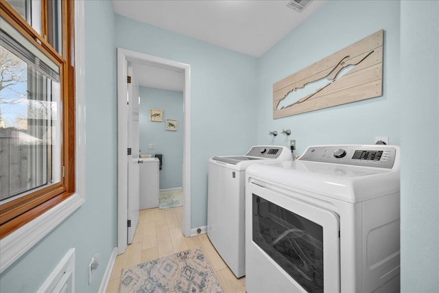 laundry area featuring washing machine and clothes dryer and light wood-type flooring