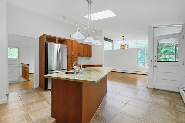 3 Dore Ct, New City, NY 10956 - kitchen with freestanding refrigerator, baseboard heating, a skylight, brown cabinets, and a kitchen island with sink