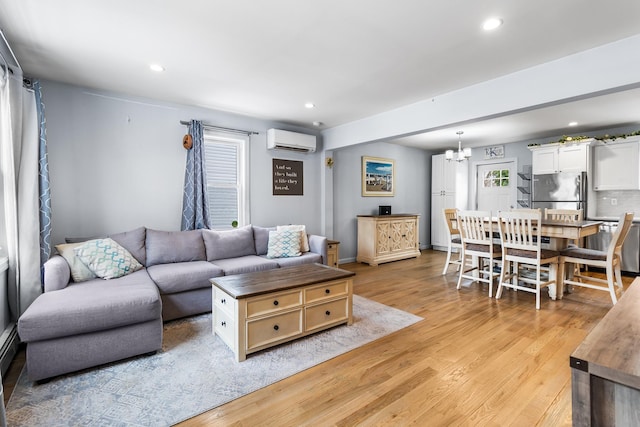 living room featuring a notable chandelier, a wall unit AC, and light hardwood / wood-style floors