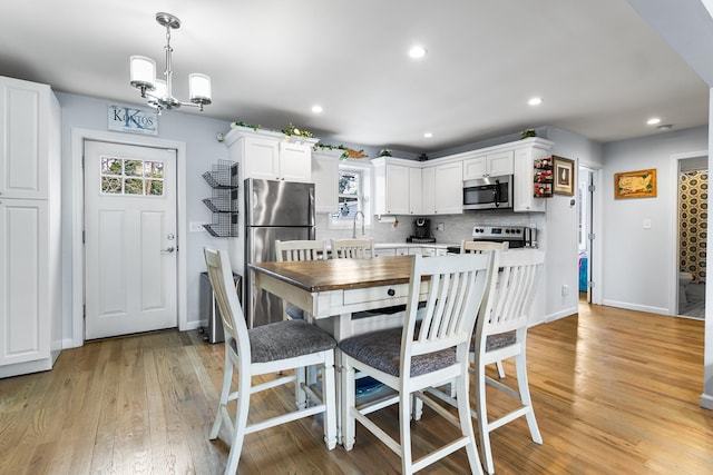 dining space featuring an inviting chandelier, sink, a wealth of natural light, and light hardwood / wood-style floors