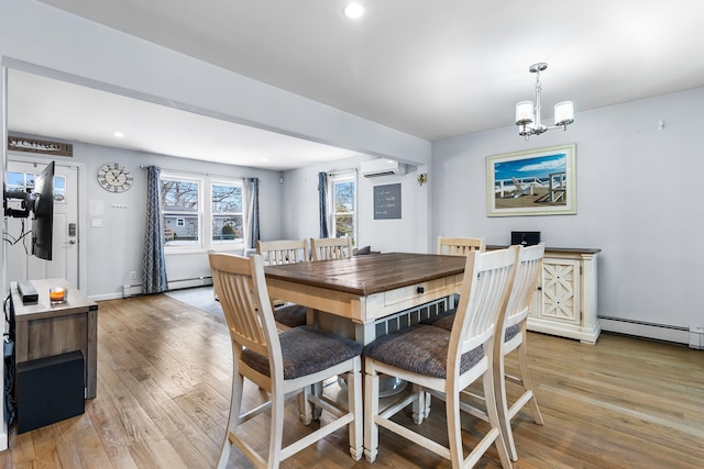 dining space featuring a baseboard radiator, a wall mounted air conditioner, a chandelier, and light wood-type flooring