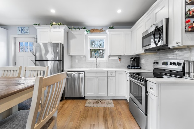 kitchen with appliances with stainless steel finishes, sink, white cabinets, and plenty of natural light