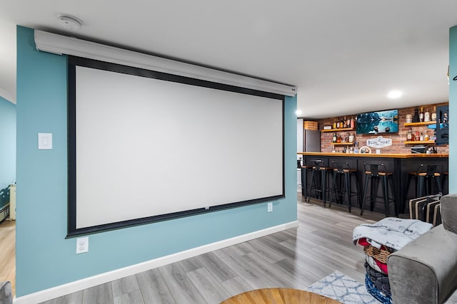 cinema with indoor bar and light hardwood / wood-style flooring