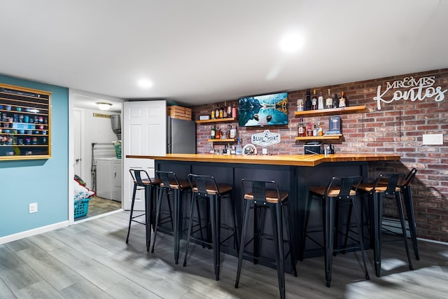 bar featuring hardwood / wood-style flooring, washer and dryer, stainless steel fridge, and wood counters