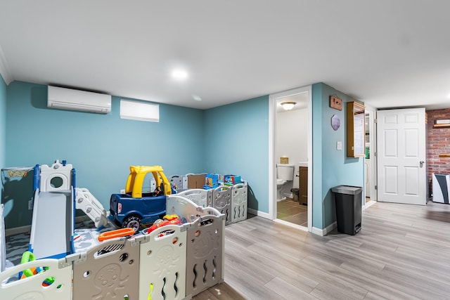 playroom featuring an AC wall unit and light wood-type flooring