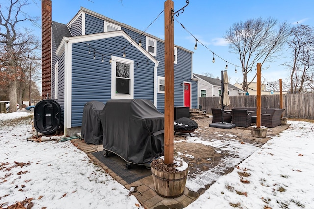 snow covered back of property with an outdoor living space with a fire pit