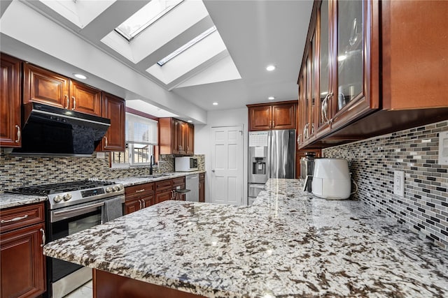 kitchen with ventilation hood, sink, decorative backsplash, stainless steel appliances, and light stone countertops