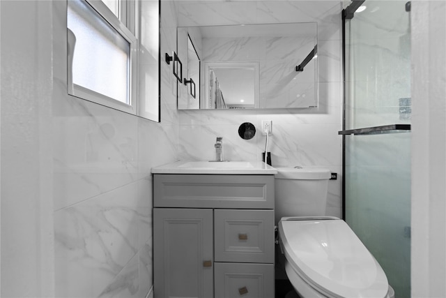 bathroom with vanity, a shower with shower door, tile walls, and toilet