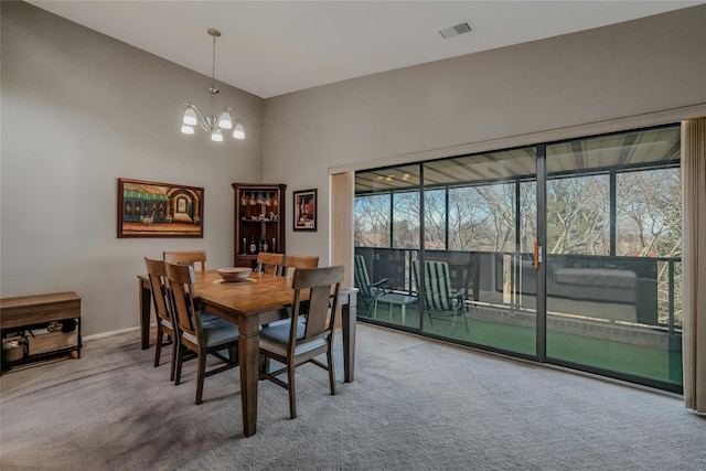 carpeted dining room featuring a notable chandelier