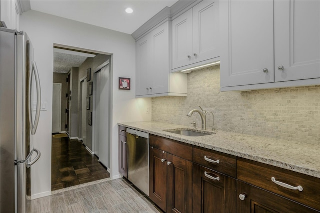 kitchen with sink, white cabinets, decorative backsplash, light stone counters, and stainless steel appliances