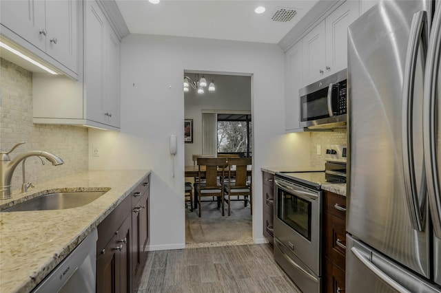 kitchen featuring sink, dark wood-type flooring, white cabinetry, stainless steel appliances, and light stone counters