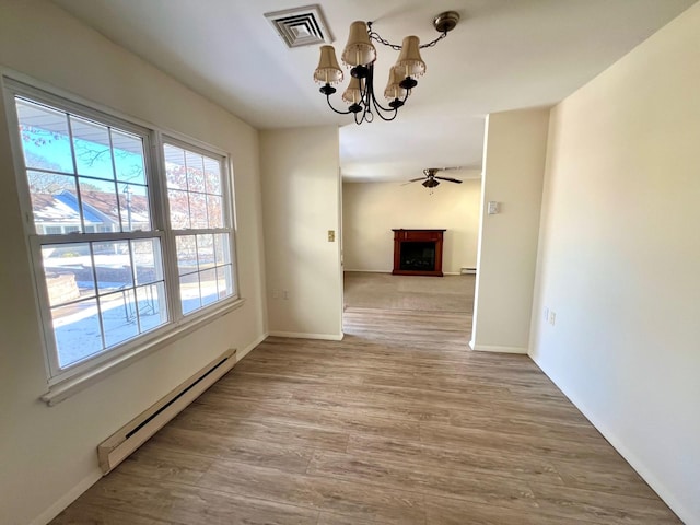 unfurnished dining area with baseboard heating, ceiling fan with notable chandelier, and light wood-type flooring