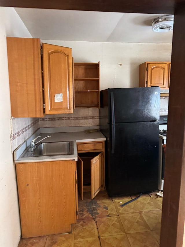 kitchen with black fridge, parquet flooring, sink, and tasteful backsplash