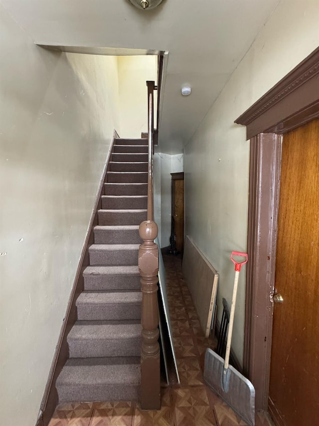 stairway featuring parquet flooring