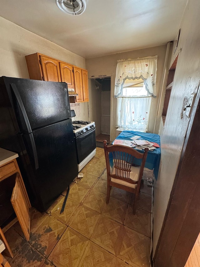 kitchen featuring black fridge, white gas range oven, and light parquet floors