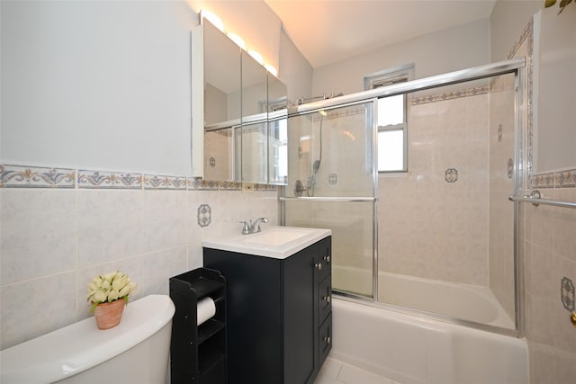 full bathroom with bath / shower combo with glass door, tile walls, vanity, and toilet