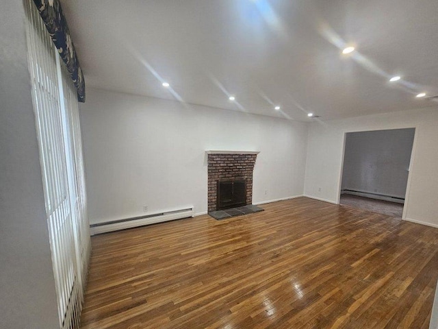 unfurnished living room featuring baseboard heating, dark hardwood / wood-style flooring, and a brick fireplace