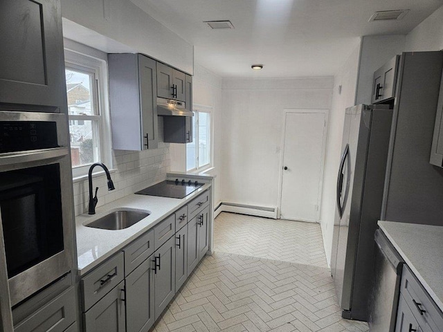 kitchen featuring a baseboard radiator, sink, gray cabinetry, backsplash, and black appliances